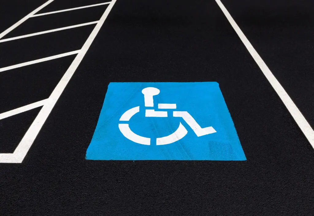 Accessible parking spot featuring blue and white pavement marking and striped loading zone