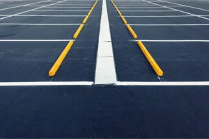 A new asphalt parking lot with fresh yellow paint and parking bollards.