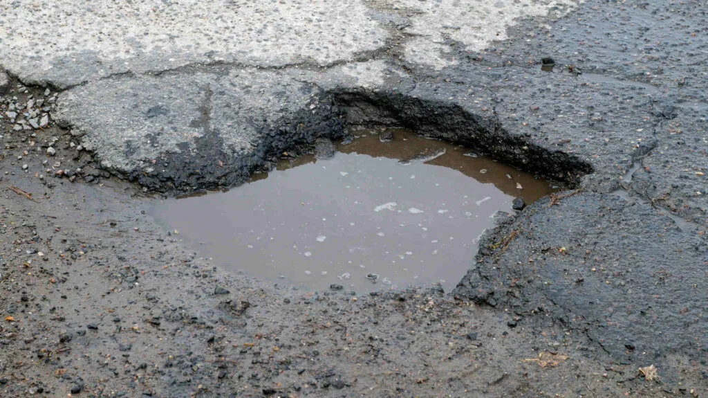 pothole with water in the middle of the street