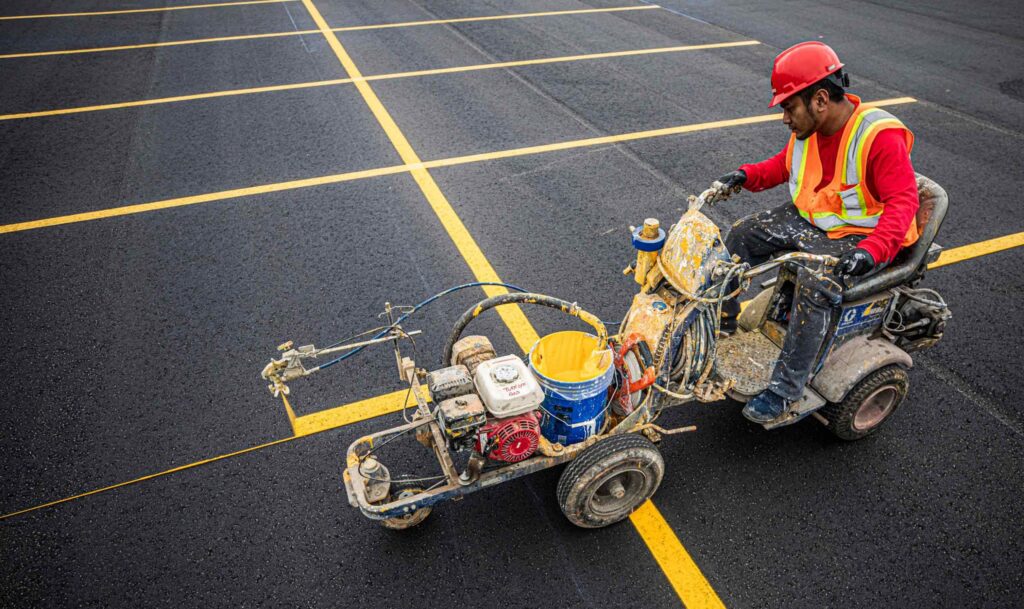 Encore Pavement worker adding striping for parking lot